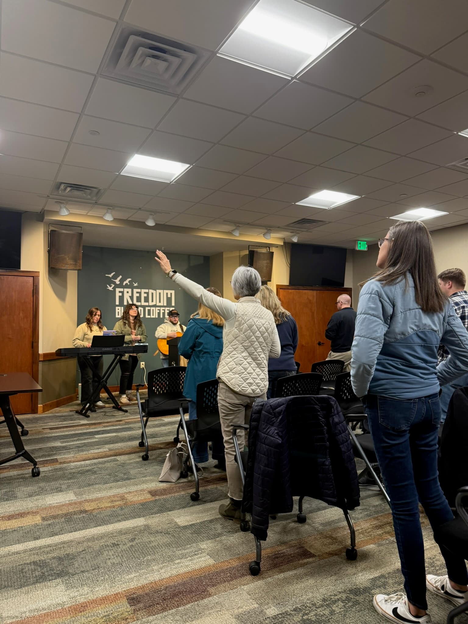 A woman in worship with hand raised at a Church For Pastors gathering.